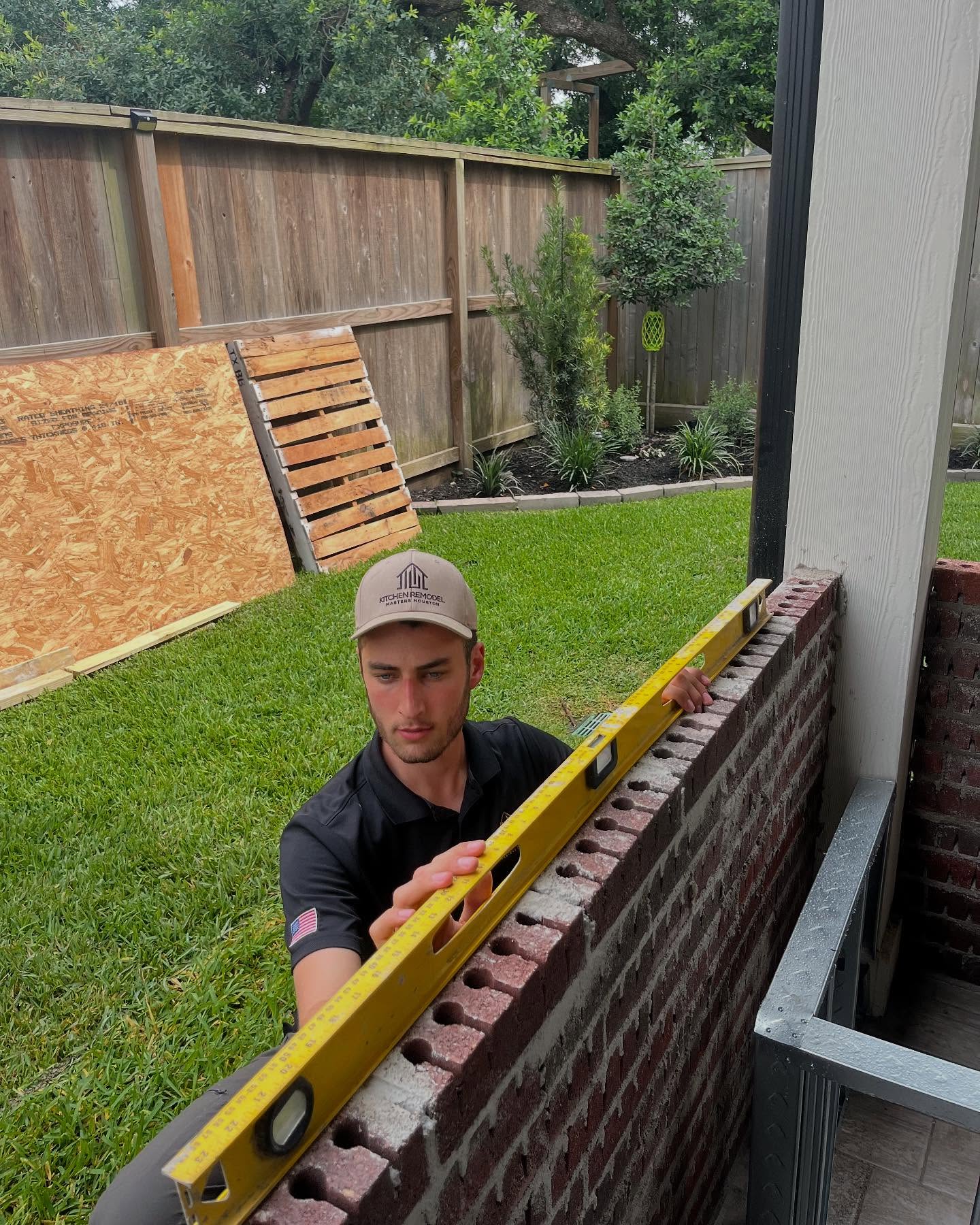 Yuval Carmel checking a brick wall with a level on a remodeling job site